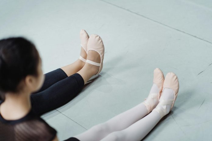 image-12 Crop ballerinas in ballet slippers sitting on floor in studio