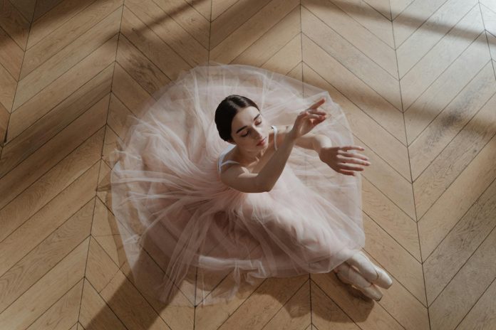 image-2 Woman in Pink Tutu Skirt Sitting on a Brown Wooden Floor