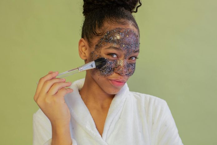 image-28 Positive black woman applying sparkling face mask with brush