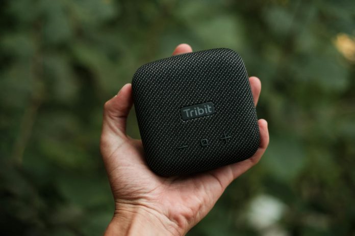 image-69 Crop unrecognizable person demonstrating contemporary square shaped portable loudspeaker near trees in daylight