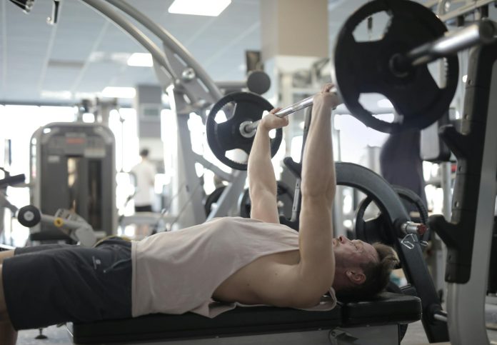 image-86 Muscular sportsman training with heavy barbell during weightlifting workout in modern gym