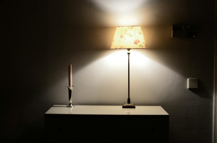 image-121 Interior of room in retro style with glowing lamp near candle in holder on shelf