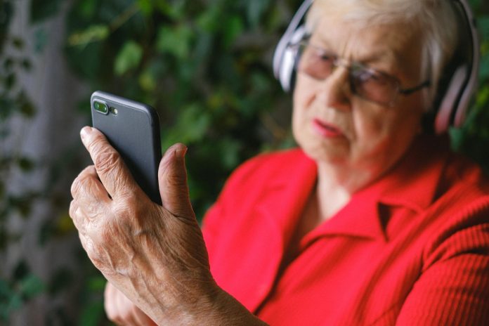 image-61 A Man in Red Shirt Using a Phone while Wearing Headphones