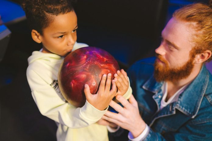 image-99 Boy Holding a Bowling Ball Beside a Man