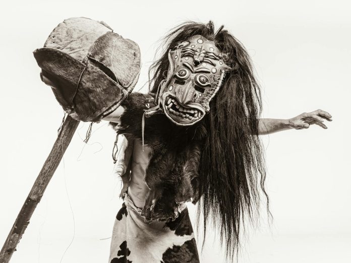 image-33 Sepia Toned Studio Shot of a Man in a Fur Carnival Costume and Mask with a Stick