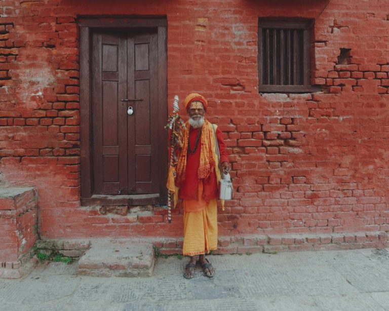 A woman in orange clothing standing in front of a red brick building